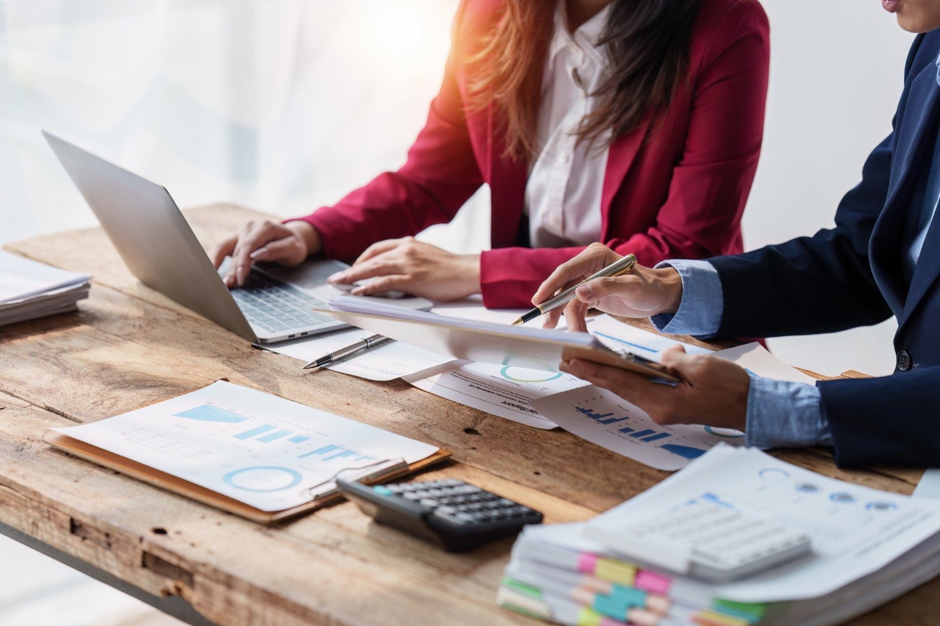 Un hombre y una mujer están sentados en una mesa con una computadora portátil y papeles.