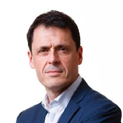 Un hombre con traje azul y camisa blanca mira a la cámara.