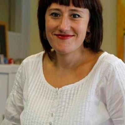 Una mujer lleva una camisa blanca y sonríe a la cámara.