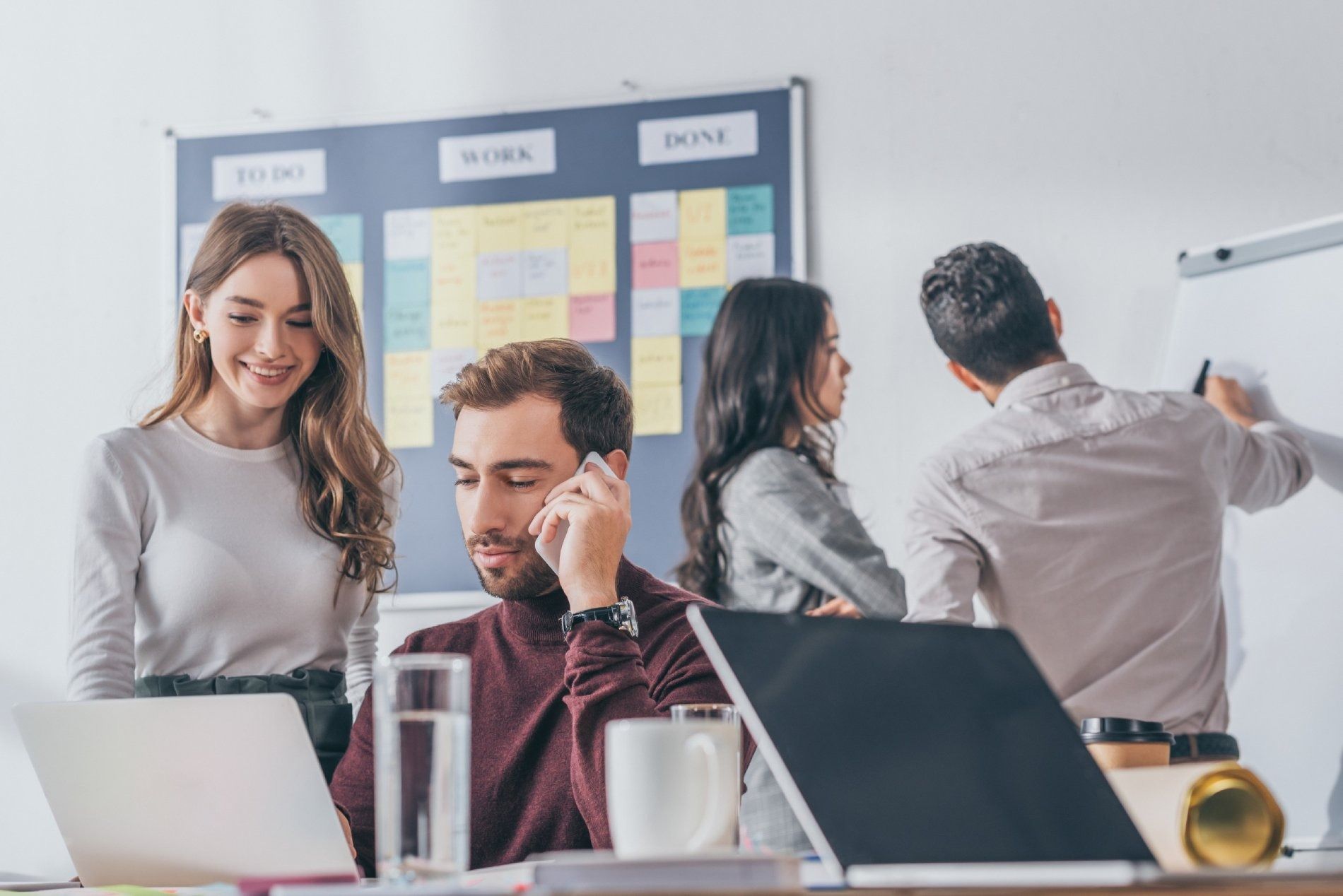 Un grupo de personas están de pie alrededor de una mesa con computadoras portátiles.