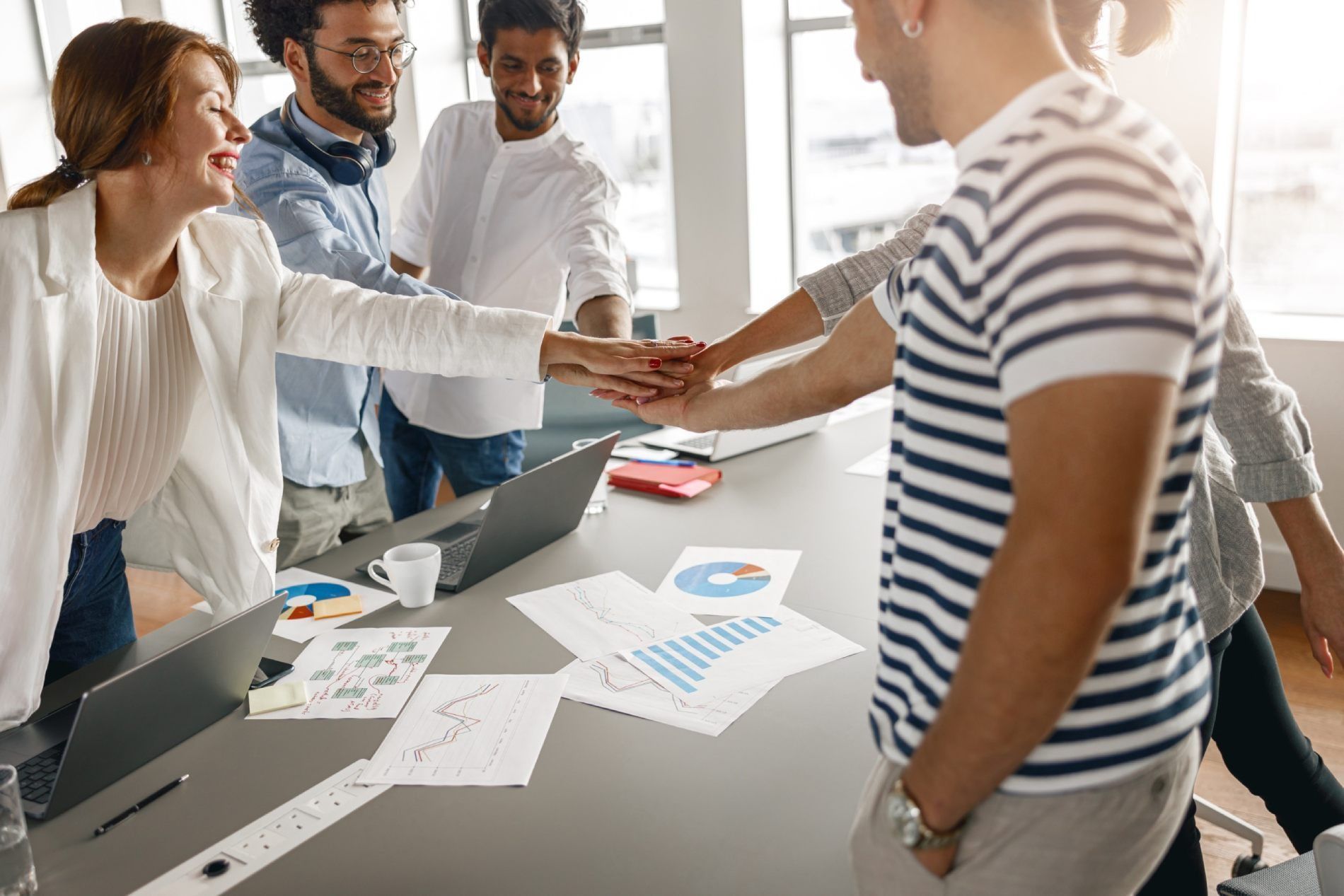 Un grupo de personas juntan sus manos en una oficina.